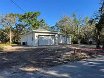 New construction home with white stucco and a two car garage in a partially wooded lot at 9229 Creston Ave, New Port Richey, FL 34654