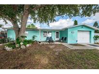 Light teal single story home with a large tree and white picket fence at 1511 Plum Tree Rd, Holiday, FL 34690