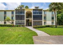 Two-story building with screened balconies and a landscaped lawn at 3232 Lake Pine E Way # H2, Tarpon Springs, FL 34688