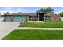 Two-story house with a three-car garage and landscaped yard at 6096 Kinlock Ave, Spring Hill, FL 34608