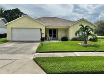 A charming yellow brick ranch-style home with a white garage door and well-manicured lawn at 4713 Tiburon Dr, New Port Richey, FL 34655