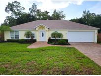 House exterior featuring a two-car garage and landscaped yard at 6075 Shingler Ave, Spring Hill, FL 34608
