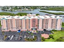 Aerial view of a large, light peach colored condominium building with parking and waterfront views at 4516 Seagull Dr # 414, New Port Richey, FL 34652