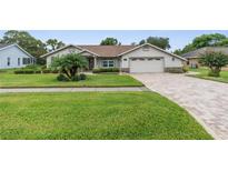 Single-story home with landscaped lawn, paver driveway, and two-car garage at 13446 Newcastle Ave, Spring Hill, FL 34609