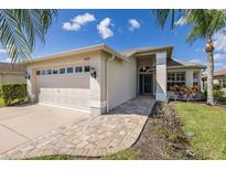 Single story home with tan exterior, light colored garage door and a paved walkway at 1633 Arbor Knoll Loop, Trinity, FL 34655