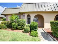 Tan condo with arched entryway and lush landscaping at 4129 Stratford Dr # 4129, New Port Richey, FL 34652