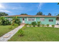 Light teal single story home with a well manicured lawn and walkway at 800 61St N St, St Petersburg, FL 33710