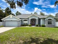 Gray house with a red door and a landscaped yard at 11298 Furley Ave, Weeki Wachee, FL 34613