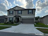 Two-story house with gray siding, two-car garage, and landscaping at 15434 Miller Creek Dr, Sun City Center, FL 33573
