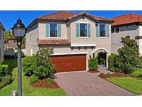 Two-story home with a red tile roof, brick driveway, attached garage, and arched front door at 3893 Burdick Loop, Odessa, FL 33556