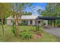 Charming ranch home with metal roof, carport, and landscaped yard at 18212 Montour Dr, Hudson, FL 34667