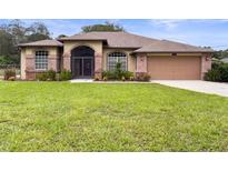 Brick house with a two car garage and lush front yard at 5481 Nodoc Rd, Spring Hill, FL 34609