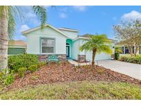 Light teal house with landscaping, driveway, and palm trees at 11143 Merganser Way, New Port Richey, FL 34654