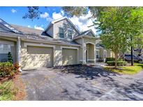 Tan two-story townhome with a two-car garage and mature trees in the front yard at 3605 Kings Rd # 102, Palm Harbor, FL 34685