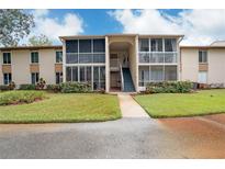 Exterior of a two-story condo building with a walkway and landscaped lawn at 12119 Sunny Glen Ln # H1, Hudson, FL 34669