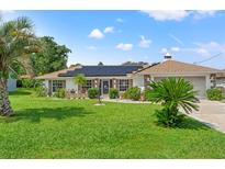 Single-story home with solar panels, landscaped lawn, and two-car garage at 3077 Ardenwood Dr, Spring Hill, FL 34609
