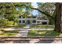 Two-story house with a wrap-around porch and mature trees at 321 S Brooksville Ave, Brooksville, FL 34601
