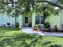 Landscaped front yard with walkway to light green house at 13740 Coronado Dr, Spring Hill, FL 34609