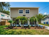 Two-story house with light brown siding, palm trees, and a well-manicured lawn at 313 Crystal Beach Ave, Crystal Beach, FL 34681