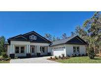 Charming, light two-story home with a manicured lawn and paver driveway under a bright, cloudless blue sky at 6109 Dusk Rose Ln, Brooksville, FL 34601