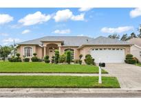 One-story house with beige exterior, gray roof, and a two-car garage at 8651 Kipling Ave, Hudson, FL 34667