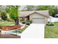 Charming home with well-manicured landscaping, a brick facade, and a screened-in pool at 6206 Soaring Ave, Temple Terrace, FL 33617