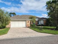 Brick home with two-car garage and landscaped yard at 2484 Misty Meadow Ct, Spring Hill, FL 34606