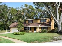Tan house with brown roof, attached garage, and spacious lawn at 15473 Darien Way, Clearwater, FL 33764