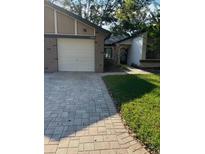 Exterior view of a villa with a brick facade, attached garage, and landscaped lawn at 7486 Heather Walk Dr # 31, Weeki Wachee, FL 34613