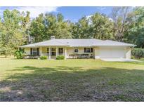 Single story house with metal roof, attached garage, and large yard at 13080 Old Crystal River Rd, Brooksville, FL 34601