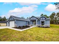 Newly constructed home with gray exterior, stone accents, and a two-car garage at 12260 Quigley Ave, Weeki Wachee, FL 34614