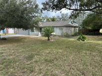 House with a large front yard, landscaping, and driveway at 8353 Forest Oaks Blvd, Spring Hill, FL 34606
