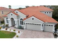 Beautiful two-story home featuring a three-car garage, red tile roof, and manicured landscaping at 10441 Garda Dr, Trinity, FL 34655