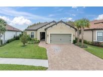 Tan house with gray garage door and landscaping; a paved driveway leads to the home at 10693 Calluna Dr, Odessa, FL 33556