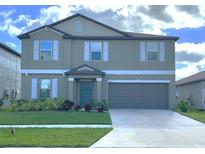 Two-story home with a neutral exterior, two-car garage, and well-maintained lawn at 9423 Channing Hill Dr, Sun City Center, FL 33573