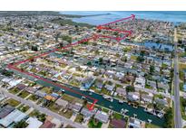 Aerial view of waterfront homes with boat docks and canal access in a coastal community marked with red path to open water at 13639 Frances Ave, Hudson, FL 34667