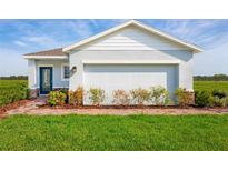 Single-story home with light blue exterior, brick walkway, and two-car garage at 2466 White Ladyfish Rd, Wimauma, FL 33598