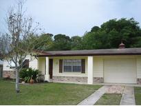 Ranch-style home with carport, mature trees, and well-maintained lawn at 3605 Richboro Dr, Holiday, FL 34691