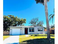 Newly renovated home with a white garage door and red front door, featuring a well-manicured lawn at 7142 Carlow St, New Port Richey, FL 34653