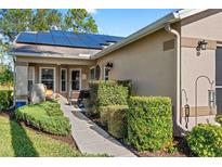 Inviting walkway to front entrance, featuring landscaping and solar panels at 1400 Summerwood Ct, Spring Hill, FL 34606