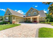 Green two-story house with a brick facade, paver driveway, and landscaping at 6128 Evening Ray Dr, Brooksville, FL 34601