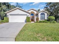 Single-story home with a two-car garage and well-manicured lawn at 11445 Deercroft Ct, Spring Hill, FL 34609