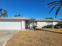 Ranch style home with a white brick facade, attached garage, and a small yard at 3249 Trask Dr, Holiday, FL 34691