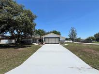 Charming single-story home featuring a white exterior, stone accents and a wide driveway at 1000 Godfrey Ave, Spring Hill, FL 34609
