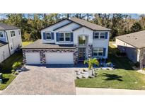 Two-story home with stone accents and a three-car garage. Landscaped yard with palm trees at 12062 Nouveau Ave, Spring Hill, FL 34610