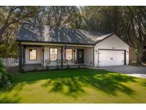 Charming one-story home with a white exterior, covered porch, and lush green lawn at 13834 Vacation Ln, Odessa, FL 33556