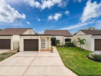 Front view of charming villa with a 1 car garage, mature landscaping and driveway at 4604 Stonehaven Pl, New Port Richey, FL 34652