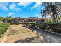 Brick house with a long driveway, hedges, and landscaping at 8700 Cessna Dr, New Port Richey, FL 34654