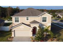 Two-story house with a red door, attached garage, and landscaping at 10167 Bankston Dr, Hudson, FL 34667