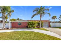 Brick ranch home with circular driveway, landscaping, and palm trees at 12832 3Rd Isle, Hudson, FL 34667